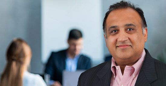 Ajoy Sharma headshot with meeting in background on how to mitigate investment risks and enhance returns